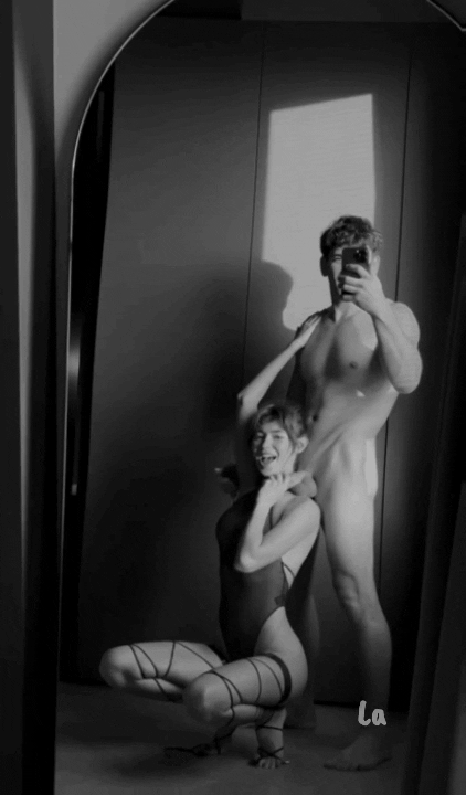 You kneel in front of the mirror, his cock resting over your shoulder as you tilt your head to rub it against your skin, the shaft sliding across you while you watch yourself in the glass. Your lips brush it, kissing the tip softly, eyes locked on your own reflection as you tease him with every move.