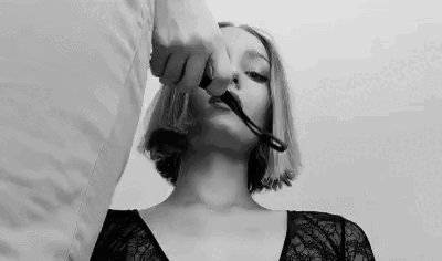 You dangle the leash in front of her, commanding her to take it between her teeth, watching as she bites down on the leather under your stern glare. Then you step forward, collar in hand, and fasten it around her neck with a rough snap, yanking the leash from her mouth to cement your dominance over her.